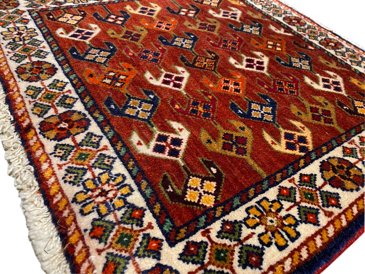 Rug with a red patterned field, blue-turquoise border, and frayed edging