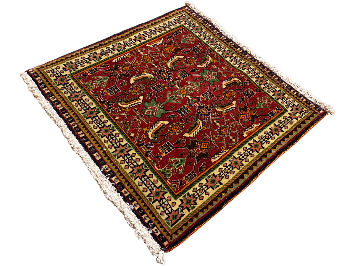 Poshti rug 63x61 cm, diagonal close-up: red rug with ornaments and fringes.