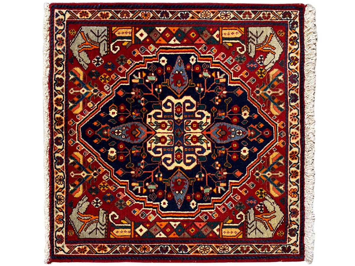 Square rug with a red background, a blue star pattern, and decorative borders