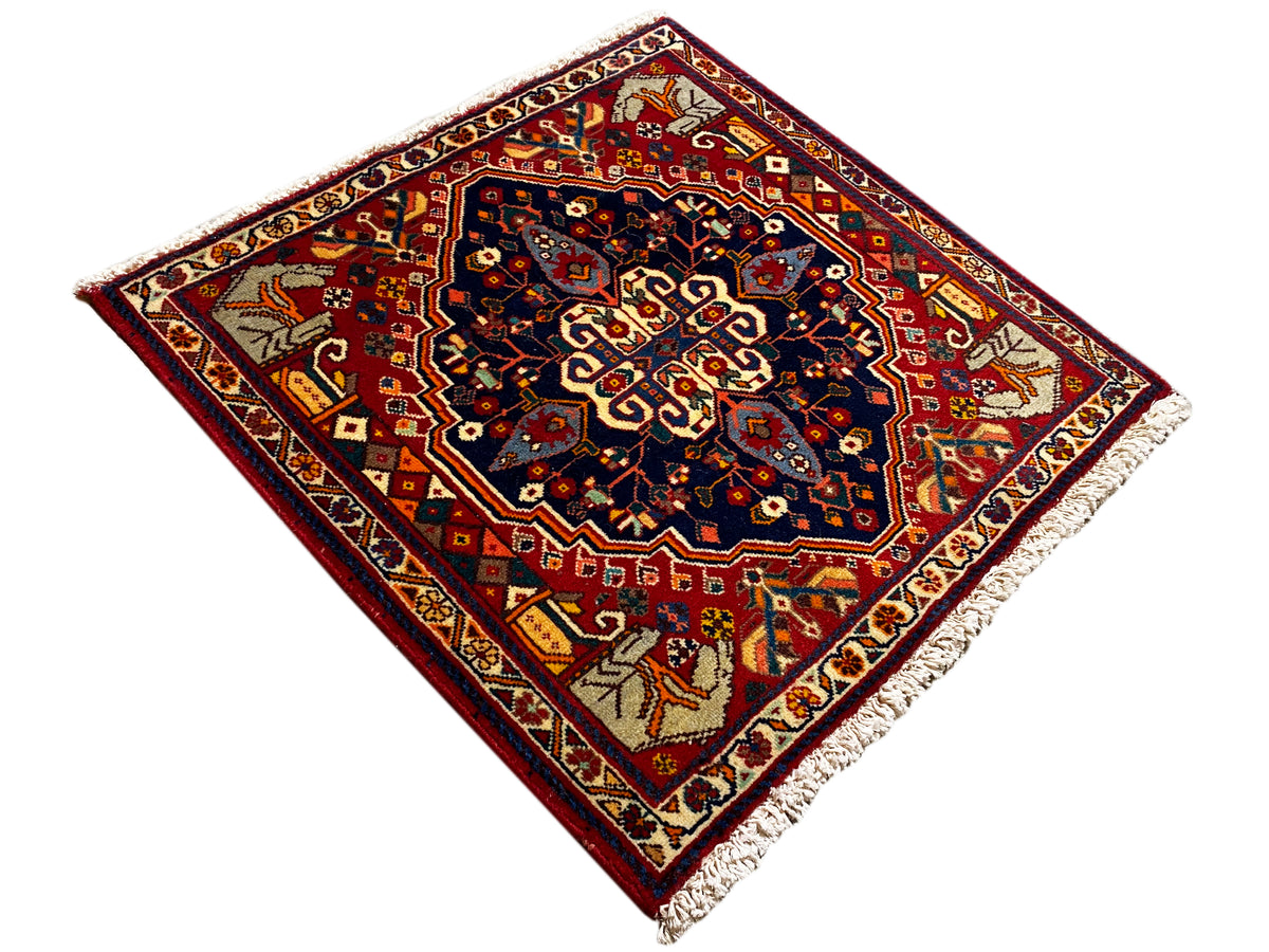 Rug in a diagonal composition: red border with blue center, corner motifs and fringes