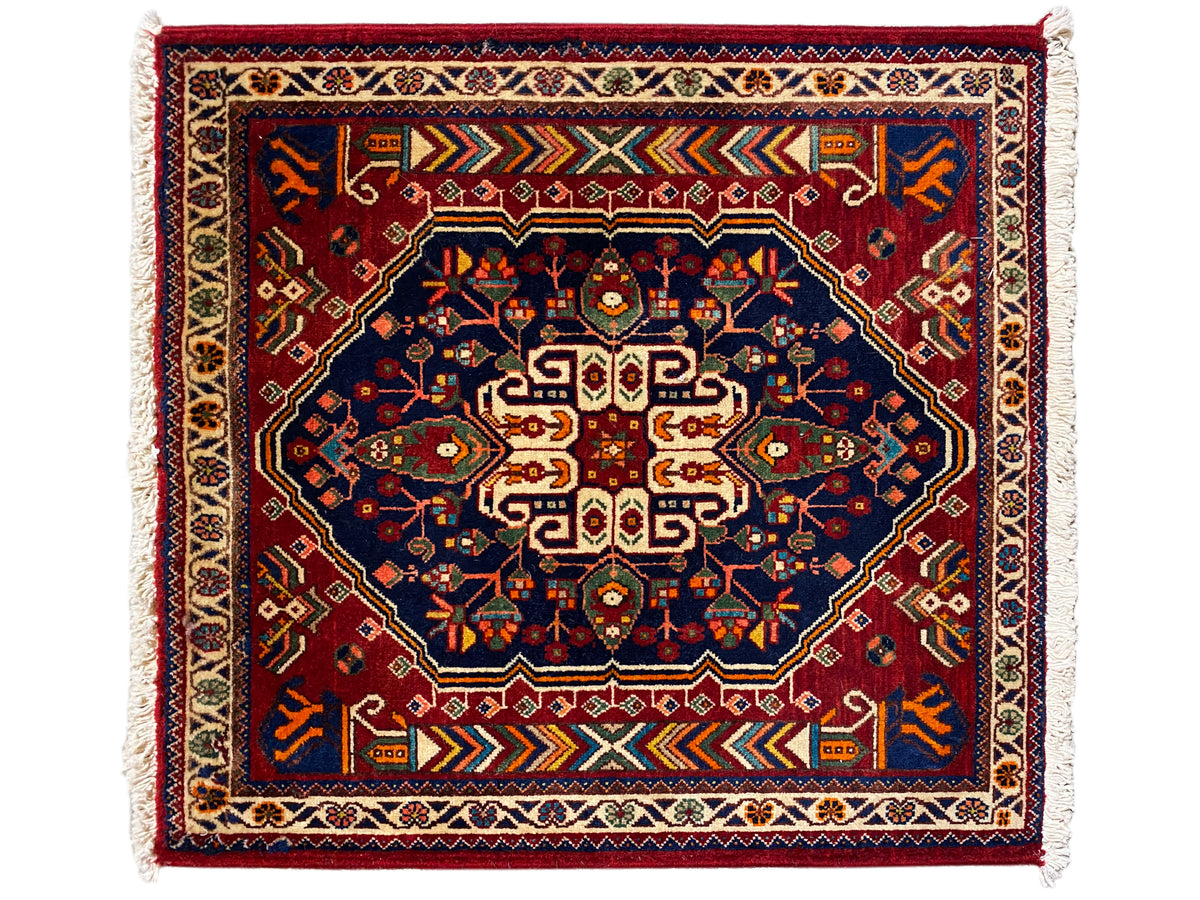 Dark blue 63x60 cm rug with red pattern, border stripes, and fringes