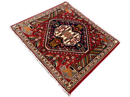 Oriental rug with a red background, cream-colored patterns, and colorful decorative stripes