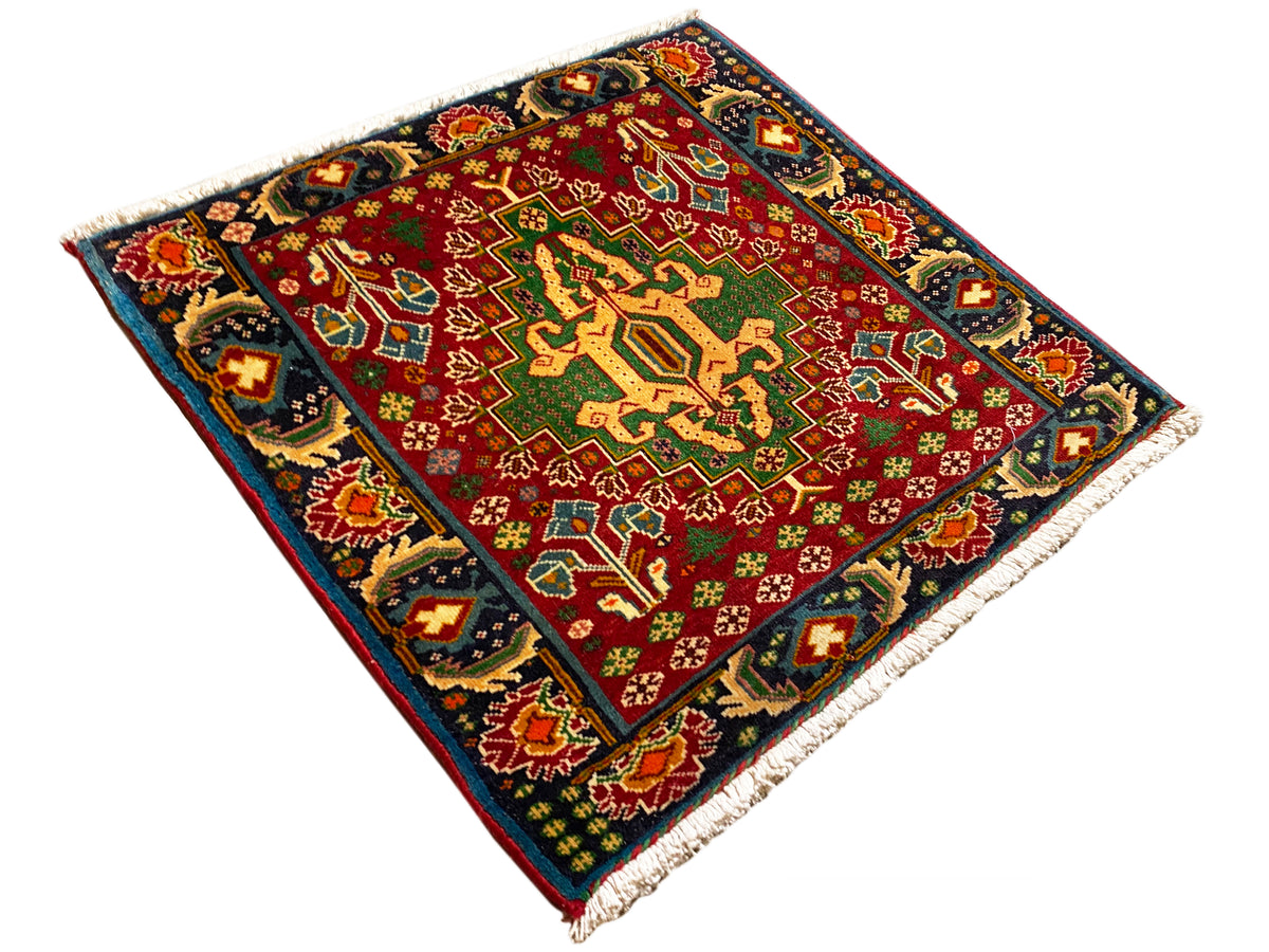 Rectangular rug (67x66 cm) photographed diagonally; red field, dark border, fringes
