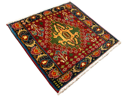 Rectangular rug (67x66 cm) photographed diagonally; red field, dark border, fringes