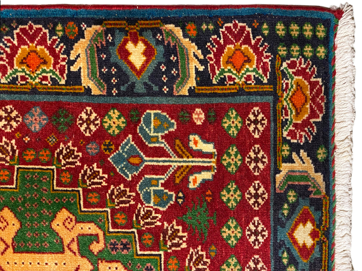 Carpet close-up: colorful ornaments on a dark background, red and green motifs, woven border