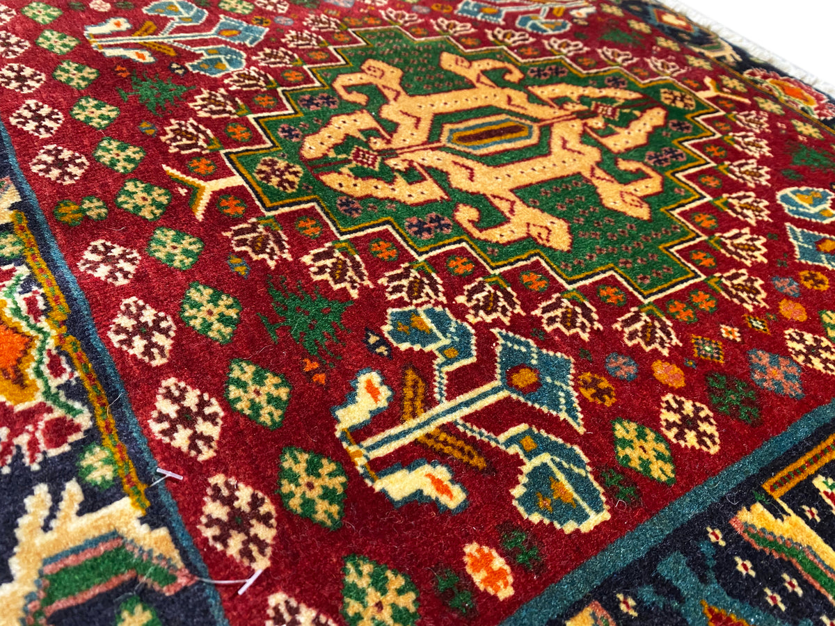 Carpet front detail with a red field, star-shaped patterns, and turquoise lines, textured pile