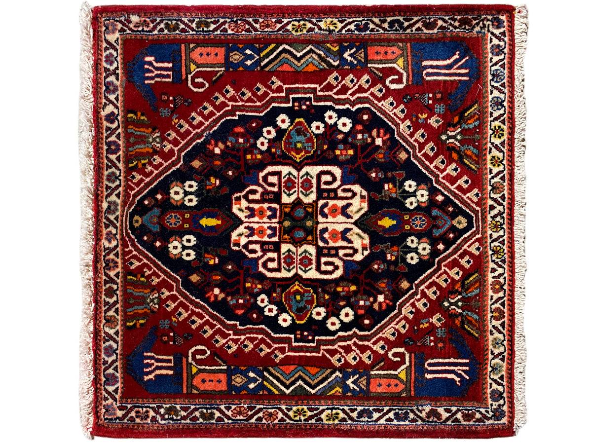 Rectangular rug with a red border, dark blue inner field, and geometric pattern