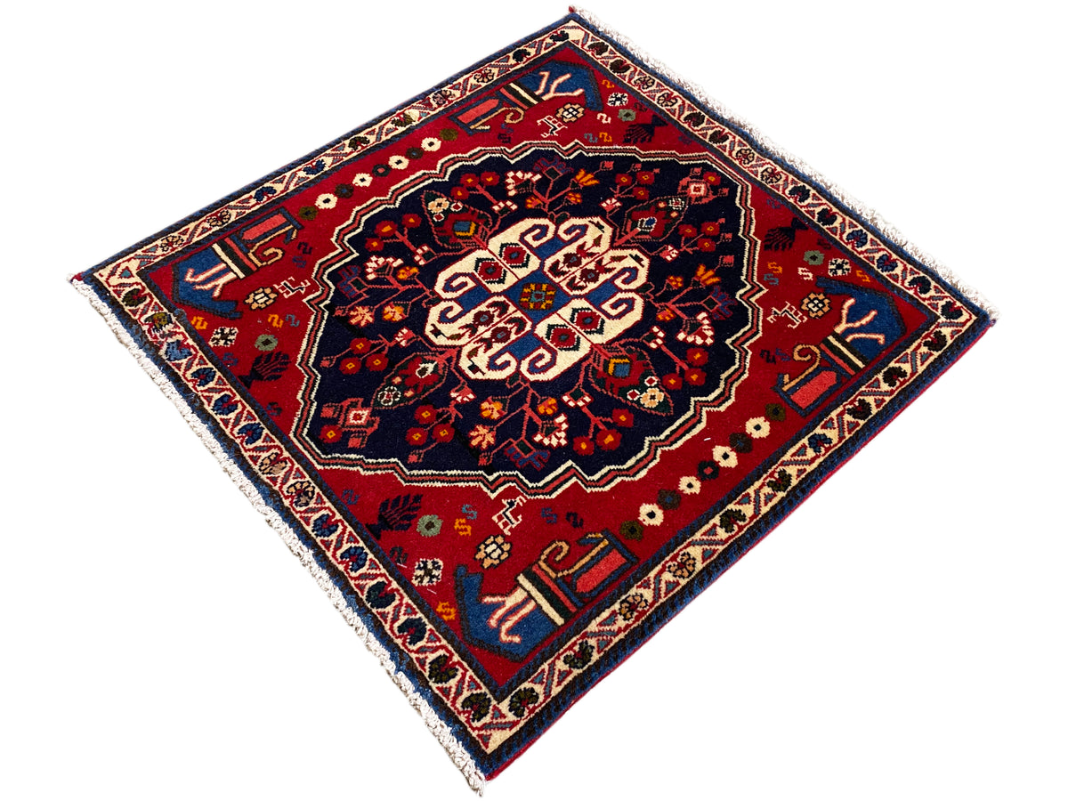 Square rug with a red center, blue border, and delicate ornamental band